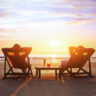 Two individuals reclining on lounge chairs at the beach during a glowing sunset, highlighting the calm that comes from safeguarding your family fortune across generations.