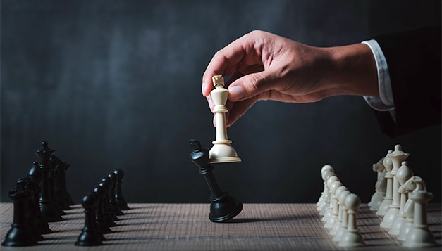 Businessman's hand captures black king with white queen on chessboard, symbolizing strategic decision-making and smarter financial moves using structured intelligence beyond instincts