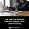 An hourglass on a wooden desk with a person working on a laptop in the background, illustrating the impact of real-time reporting on family office decision-making and efficiency